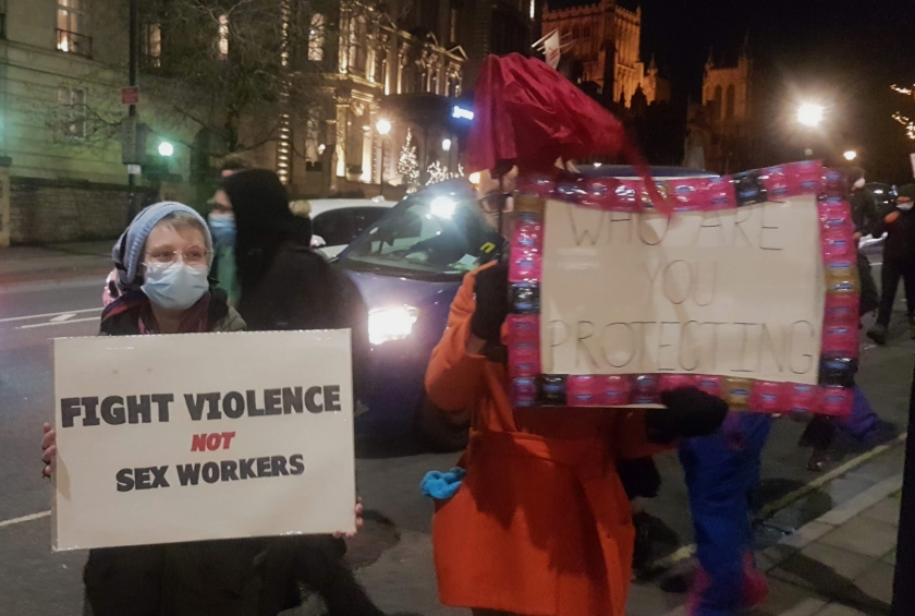 Two protesters hold placards. One says "Fight Violence not Sex Workers"
