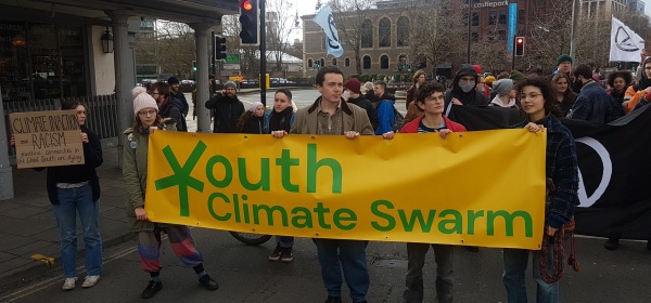 Four activists hold a banner reading "Youth Climate Swarm"