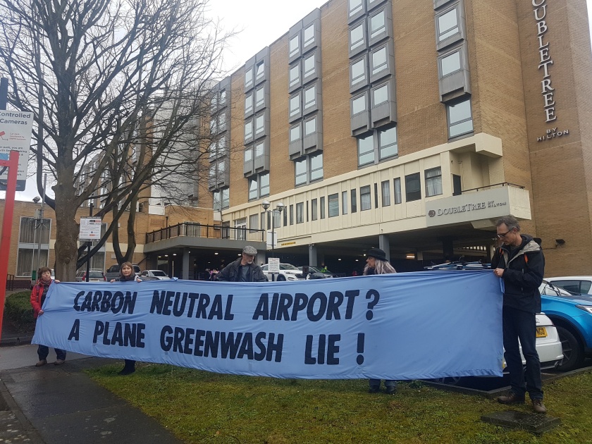 Banner reads "Carbon Neutral Airport? A Plane Greenwash Lie!"
