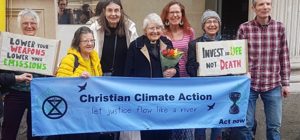 Eight people smile for the camera holding a banner which reads "Christian climate action"