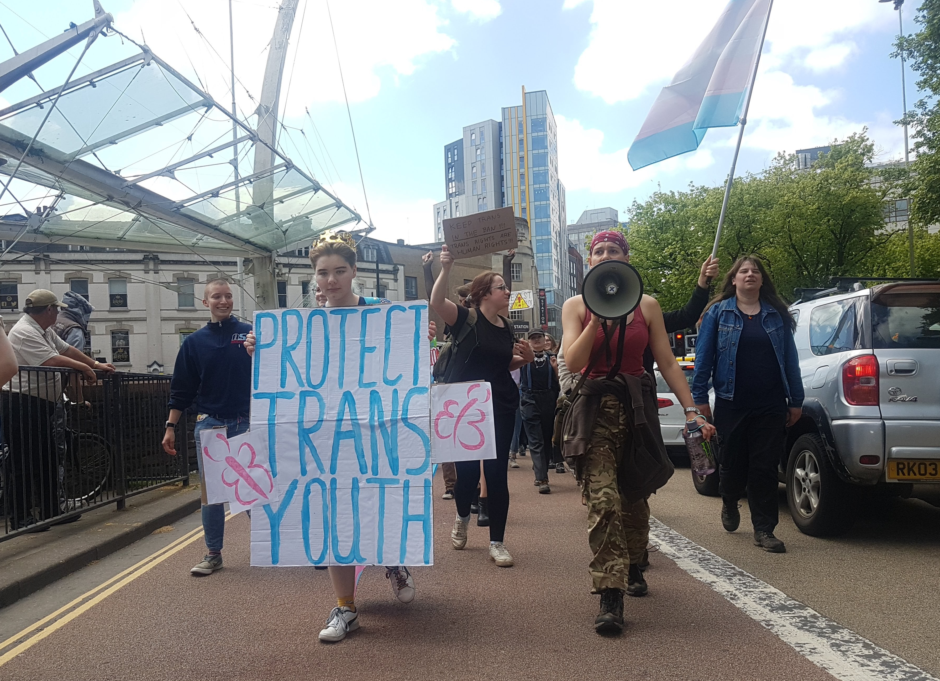 A protester holds a large placard reading "Protect Trans Youth"